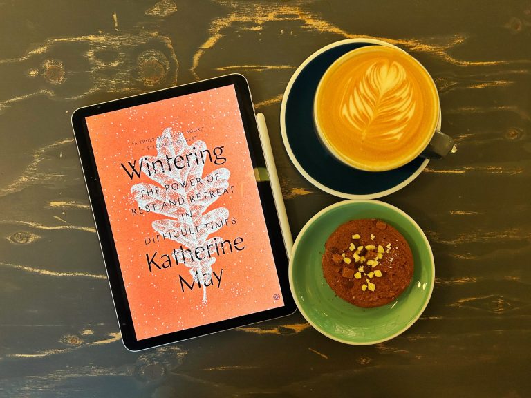 Wintering Ebook with a cup of coffee and a chocolate cookie.