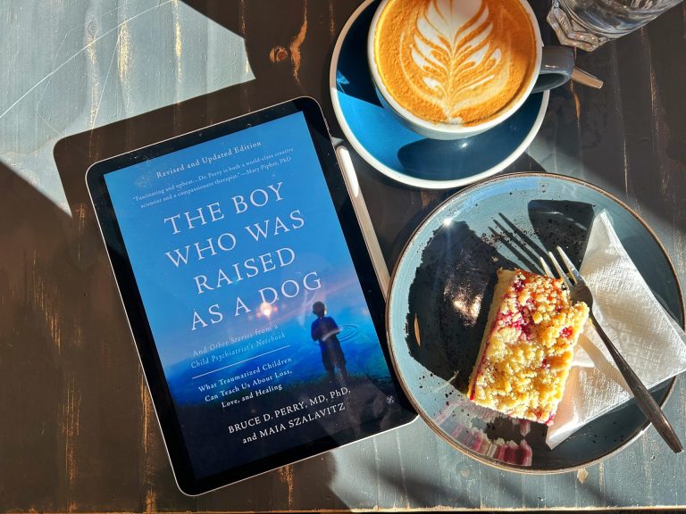 The Boy Who Was Raised as a Dog Ebook Cover beside a slice of cake and a cup of coffee