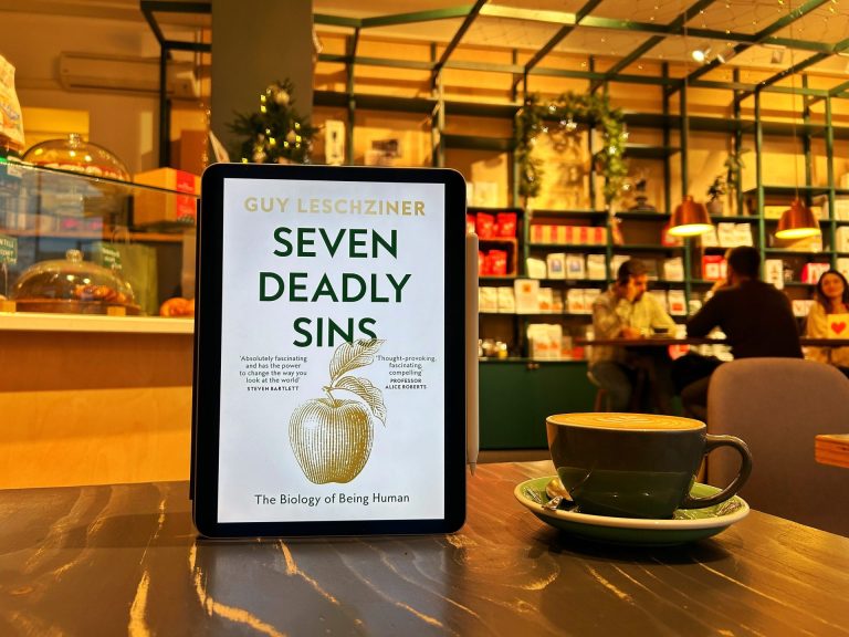 Seven Deadly Sins Book Cover on a table with a cup of coffee