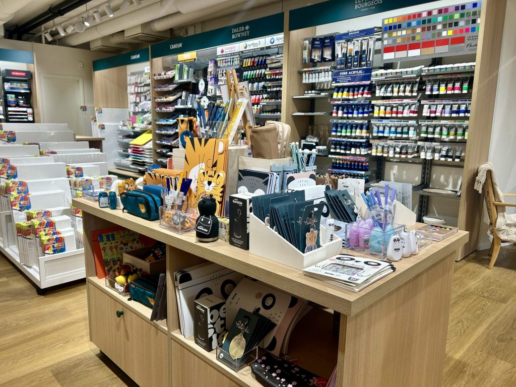 Stationery on the front shelves and art supplies on the back shelf inside a stationery store