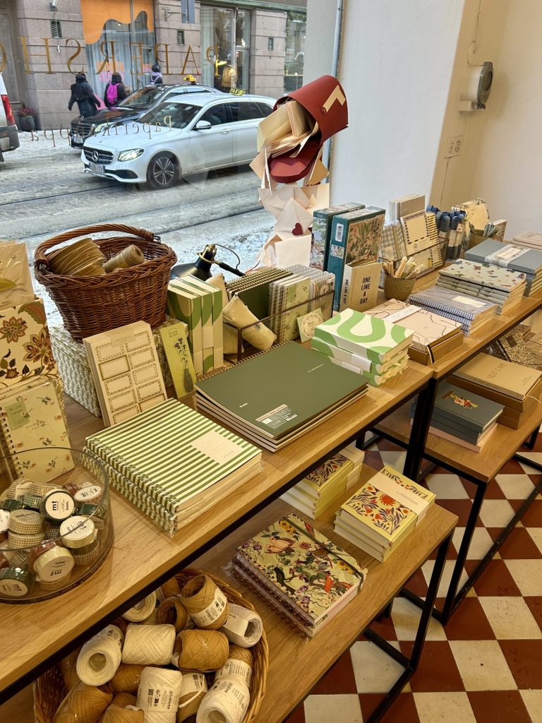 Stack of notebooks and papers with Valentine’s decorations in a papershop window