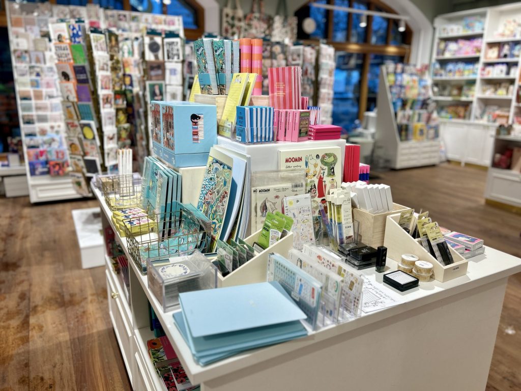 A table inside a papershop full of notebooks, papers, and sticker sheet