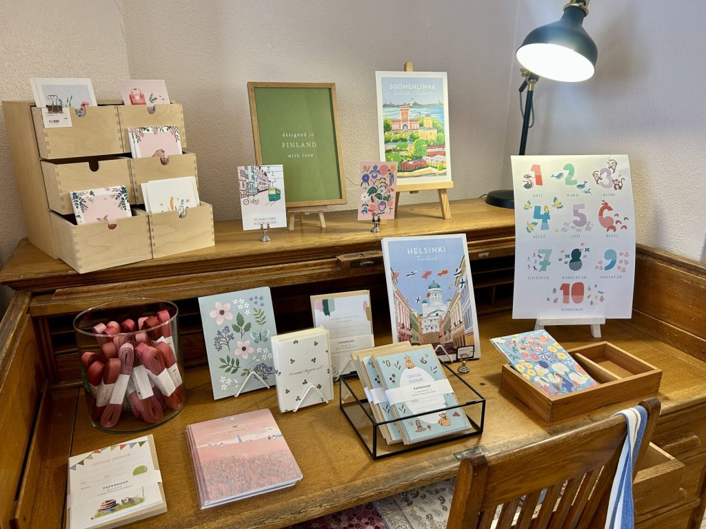 Poster, post card, invitation paper, and some accesories mainly with Finland’s theme on a desk inside a papershop