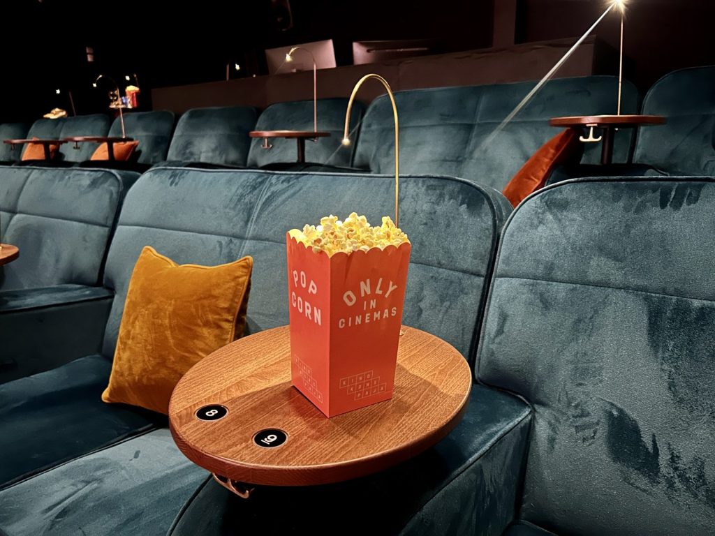 Popcorn on a table inside a movie theater with blue sofa around
