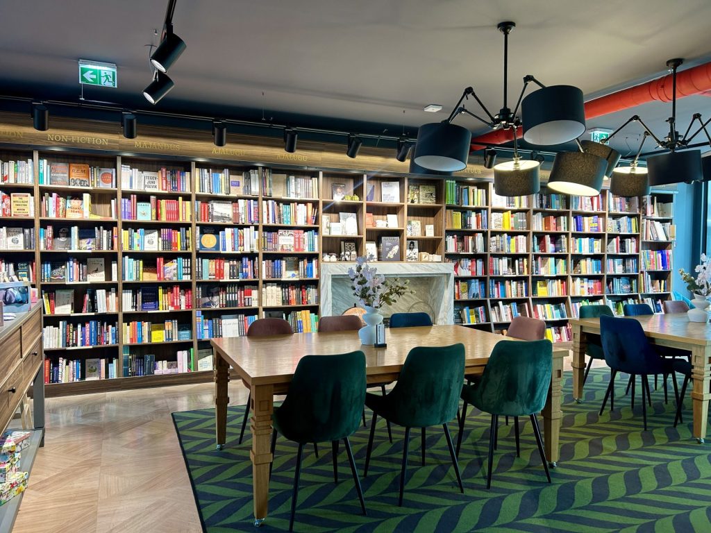 A corner in a bookstore consists of bookshelves, chairs, and a long tables.