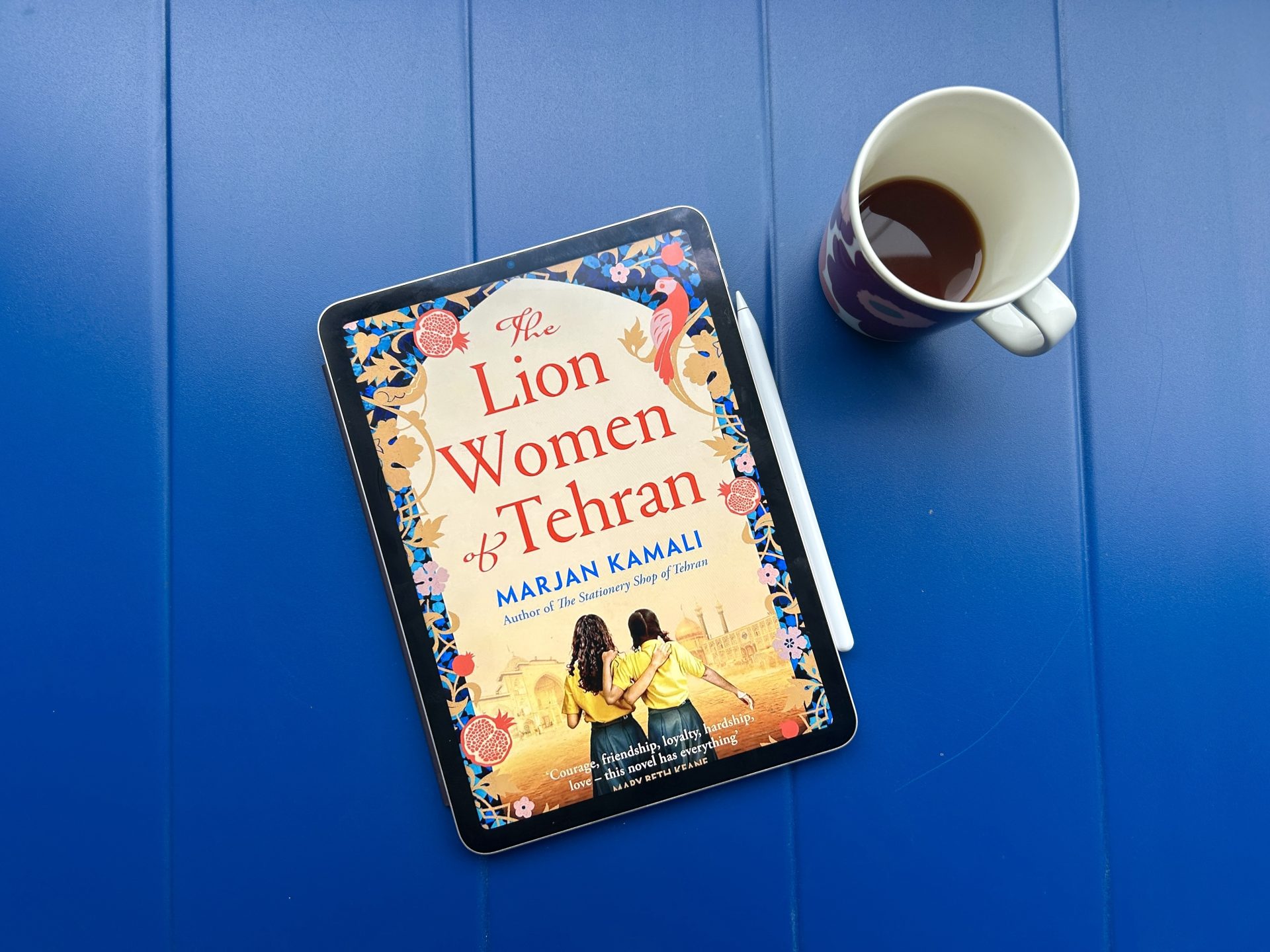 The Lion Women of Tehran eBook with a cup of coffee on a blue table