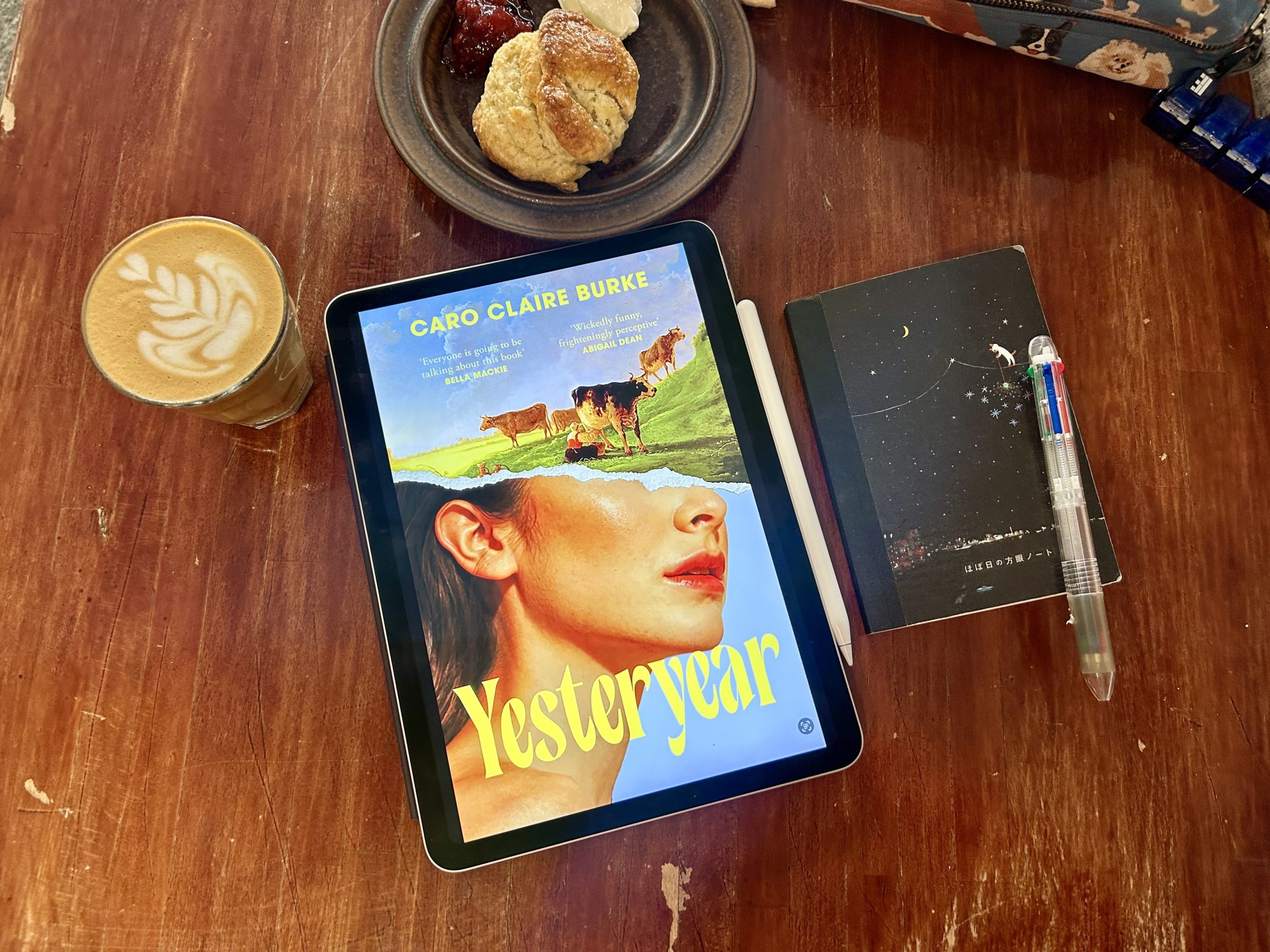 Yesteryear eBook, a notebook, a pen, and a cup of coffee on a brown wooden table
