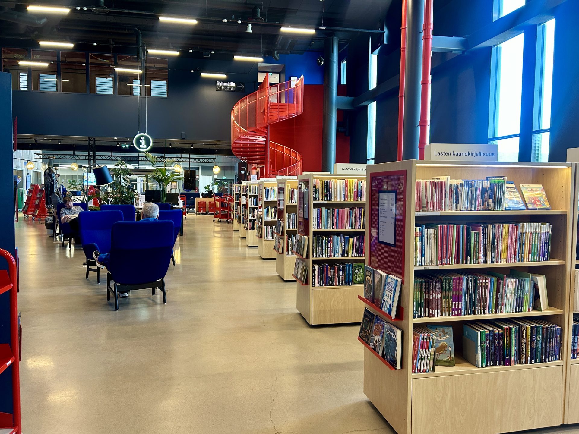 Shelfs of books inside a library with red stairs